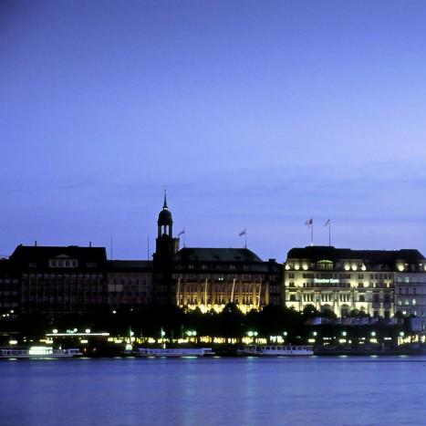 Blick auf die abendliche, hell erleuchtete Binnenalster und den Jungfernstieg; im Vordergrund die Alsterfontaine